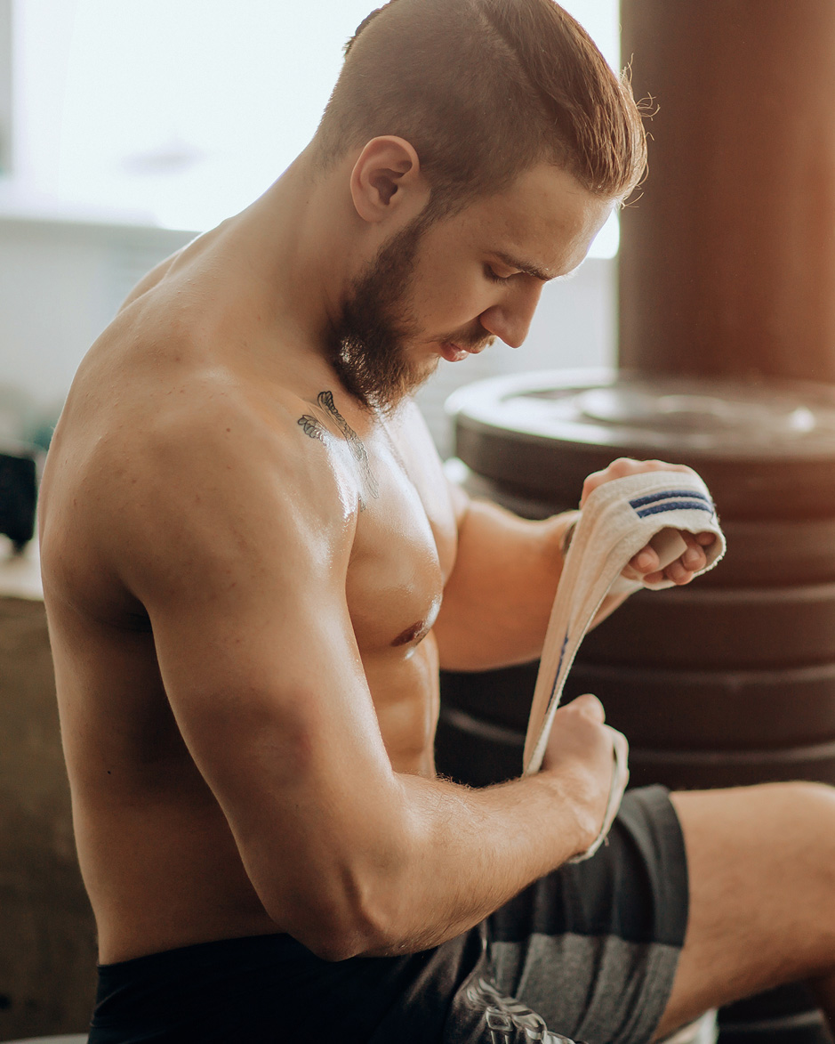Man Wrapping Hands With Boxing Wraps in Gym