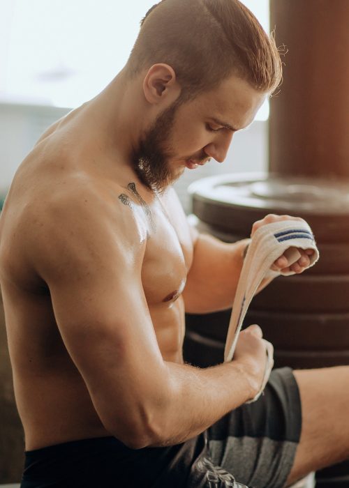 Man Wrapping Hands With Boxing Wraps in Gym